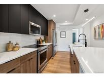 Modern kitchen with stainless steel appliances, contrasting cabinetry, and bright white countertops at 3430 W 25Th Ave, Denver, CO 80211