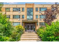 Inviting brick apartment building at 1450, with lush greenery framing the entrance at 1450 Albion St # 204, Denver, CO 80220