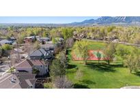 Gorgeous aerial view of neighborhood homes near a tennis court with views of the mountains and a tree-lined community at 4059 Nevis St, Boulder, CO 80301