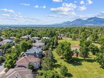 Neighborhood aerial shot, showcasing tree-lined streets, nearby park with tennis court, and mountain views in the distance at 4059 Nevis St, Boulder, CO 80301