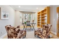 Bright home office featuring a bay window, modern desk, hardwood floors, custom bookshelf and stylish accent chairs at 4059 Nevis St, Boulder, CO 80301