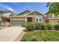 Charming single-story home featuring a stone facade, green lawn, and an attached two-car garage at 7201 W Asbury Pl, Lakewood, CO 80227