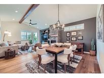 Inviting living room with a stone fireplace, wood floors, and a cozy dining area with modern chandelier at 7201 W Asbury Pl, Lakewood, CO 80227