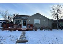 Ranch style home with snow-covered yard, deck and walkway at 11856 E 7Th Ave, Aurora, CO 80010