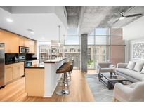 Open concept living area with hardwood floors, island with bar seating, and floor to ceiling windows at 1700 Bassett St # 703, Denver, CO 80202