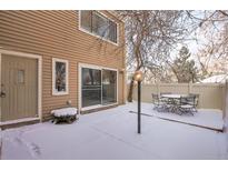 Snow covered backyard with patio furniture and a wood fence at 9573 E Kansas Cir # 57, Denver, CO 80247