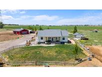 Charming home on a vast lot featuring a large front yard, red barn, and scenic countryside views at 10691 County Road 23, Fort Lupton, CO 80621