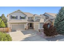 Charming two-story home featuring gray siding, stone accents, a well-manicured lawn, and attached three-car garage at 9636 W 71St Pl, Arvada, CO 80004