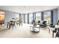 Bright living room with large windows, blue curtains, and modern furnishings; neutral tones create a cozy atmosphere at 10050 W 8Th Pl, Lakewood, CO 80215