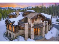 Beautiful stone and wood home featuring a balcony and mountain views in a snowy, wooded landscape at 327 Peerless Dr, Breckenridge, CO 80424