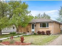 Well-kept brick home with a lush front yard, mature trees, and a welcoming pathway at 7987 Durango St, Denver, CO 80221