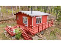 Cozy red cabin featuring a charming deck nestled in a serene wooded setting at 154 Apache Rd, Evergreen, CO 80439