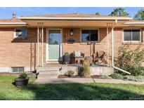 Charming brick home featuring a cozy front porch with seating and manicured landscaping at 7216 S Lincoln Way, Centennial, CO 80122