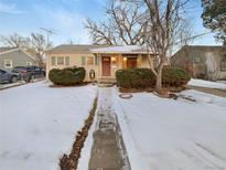 Charming single-story home featuring a cozy front porch and neat landscaping in a snowy setting at 1920 Alton St, Aurora, CO 80010