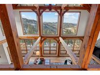 Bright living room features vaulted ceilings, wood beams, hardwood floors and expansive windows with mountain views at 13326 Kuehster Rd, Littleton, CO 80127