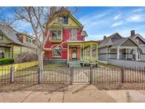 Charming red Victorian home featuring colorful trim, decorative iron fence and inviting front porch at 3424 N Marion St, Denver, CO 80205