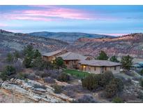 Panoramic view of home nestled in foothills, boasting natural stone and tile roof against the colors of the mountain sunset at 15175 W Belleview Ave, Morrison, CO 80465