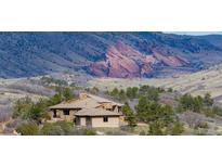 Exterior of home with tile roof nestled among trees and rolling hills, offering a peaceful retreat with scenic views at 15175 W Belleview Ave, Morrison, CO 80465
