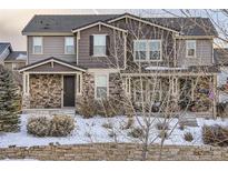 Two-story house with stone accents and a covered porch, snow-covered landscaping at 10246 Tall Oaks Cir, Parker, CO 80134