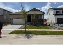 Charming single-story home featuring a manicured lawn, covered porch, and a two-car garage at 2668 Simpson Ln, Erie, CO 80026
