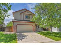 Charming two-story home with a well-maintained lawn, two-car garage, and inviting front porch at 11963 Dahlia Dr, Thornton, CO 80233