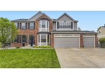 Beautiful two-story home with brick and gray siding, a well-manicured lawn, and a three-car garage at 5660 E Burlington Dr, Castle Rock, CO 80104