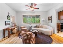 Bright living room features a ceiling fan, hardwood floors, modern furnishings, and a large window with tree views at 2100 N Franklin St # 5, Denver, CO 80205