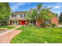 Charming two-story home boasts a beautiful front yard, brick accents, and a welcoming red front door at 1583 Sunset Ridge Rd, Highlands Ranch, CO 80126