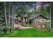 Stunning exterior view of home with stone accents, mature trees, and a manicured lawn at 4241 S Meadow Brook Ln, Evergreen, CO 80439