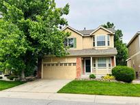 Inviting two-story home with a well-manicured lawn, mature shade tree, and attached two car garage at 6102 S Yampa St, Aurora, CO 80016
