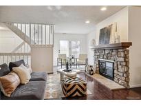 Bright living room featuring a stone fireplace, modern furniture and stairs to the second floor at 1390 S Idalia St # 39F, Aurora, CO 80017