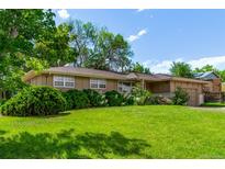 Charming single-story home with a well-manicured lawn, mature trees, and blossoming flower beds at 6131 Wolff St, Arvada, CO 80003