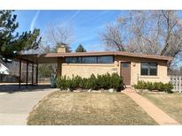 Tan brick ranch-style home with carport, landscaped front yard and a pathway to the front door at 5965 S Milwaukee Way, Centennial, CO 80121