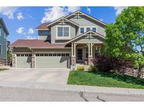 Charming two-story home with a three-car garage, lush lawn, and a welcoming front porch at 10448 Kicking Horse Dr, Littleton, CO 80125