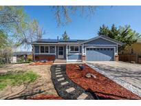 Charming blue home featuring a two-car garage, solar panels, and a beautifully landscaped front yard at 16933 E Bethany Pl, Aurora, CO 80013
