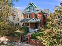 Charming two-story brick home featuring a well-manicured front yard and classic architectural details under a sunny sky at 1215 N Emerson St # A, Denver, CO 80218