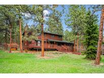 Charming two-story home with wooden deck nestled among lush trees and a well-maintained lawn at 20425 Flint Ln, Morrison, CO 80465