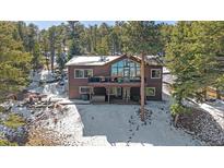 Spacious brown house nestled in a snowy forest with a deck and large windows offering scenic views at 22683 Hagler Dr, Golden, CO 80401