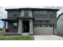 Charming two-story home featuring a gray exterior, stone accents, and a two-car garage at 3070 S Poppy St, Morrison, CO 80465