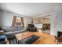 Inviting living room featuring hardwood floors, a comfortable couch, and an open view into the adjacent dining area at 1781 Ruth Dr, Thornton, CO 80229