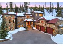 Stunning stone home with a three-car garage, red doors, and stairs leading to the front door at 118 Gold Piece Dr, Breckenridge, CO 80424