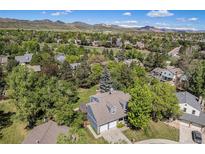 An aerial view of a home nestled among lush trees with a scenic mountain backdrop at 10247 W Roxbury Pl, Littleton, CO 80127