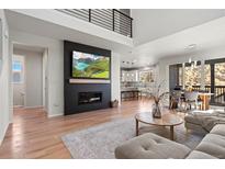 Bright, open-concept living room with a modern fireplace, wood floors, and access to the dining area and kitchen at 1044 Oleander St, Castle Rock, CO 80109