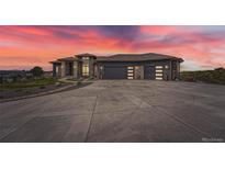 Spectacular home boasting a modern design with a spacious driveway and mountain views at sunset at 10689 Shadow Pines Rd, Parker, CO 80138