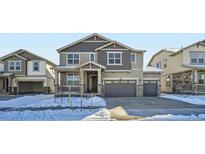 Two-story house with gray siding, a double-car garage, and a snowy front yard at 4620 Thistle Dr, Brighton, CO 80601