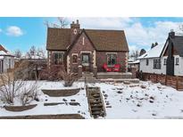 Charming brick home with snowy front yard and steps leading to the entrance at 5035 W 32Nd Ave, Denver, CO 80212