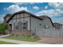 Side view of a home with stone accents, a fenced yard, and low-maintenance landscaping in a suburban setting at 6612 N Ceylon St, Denver, CO 80249