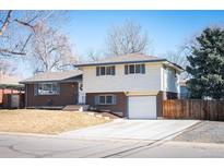 Charming two-story home featuring brick and white siding, a well-maintained lawn, and an attached garage on a sunny day at 1492 S Dudley St, Lakewood, CO 80232