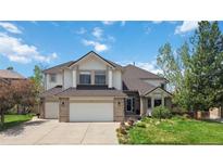 Charming two-story home featuring a well-manicured lawn, a three-car garage, and a beautiful brick and siding facade at 11302 E Ida Ct, Englewood, CO 80111
