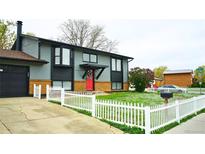 Charming two-story home with gray siding, red door, brick accents and a white picket fence creating a welcoming curb appeal at 1528 Coronado Pkwy, Denver, CO 80229